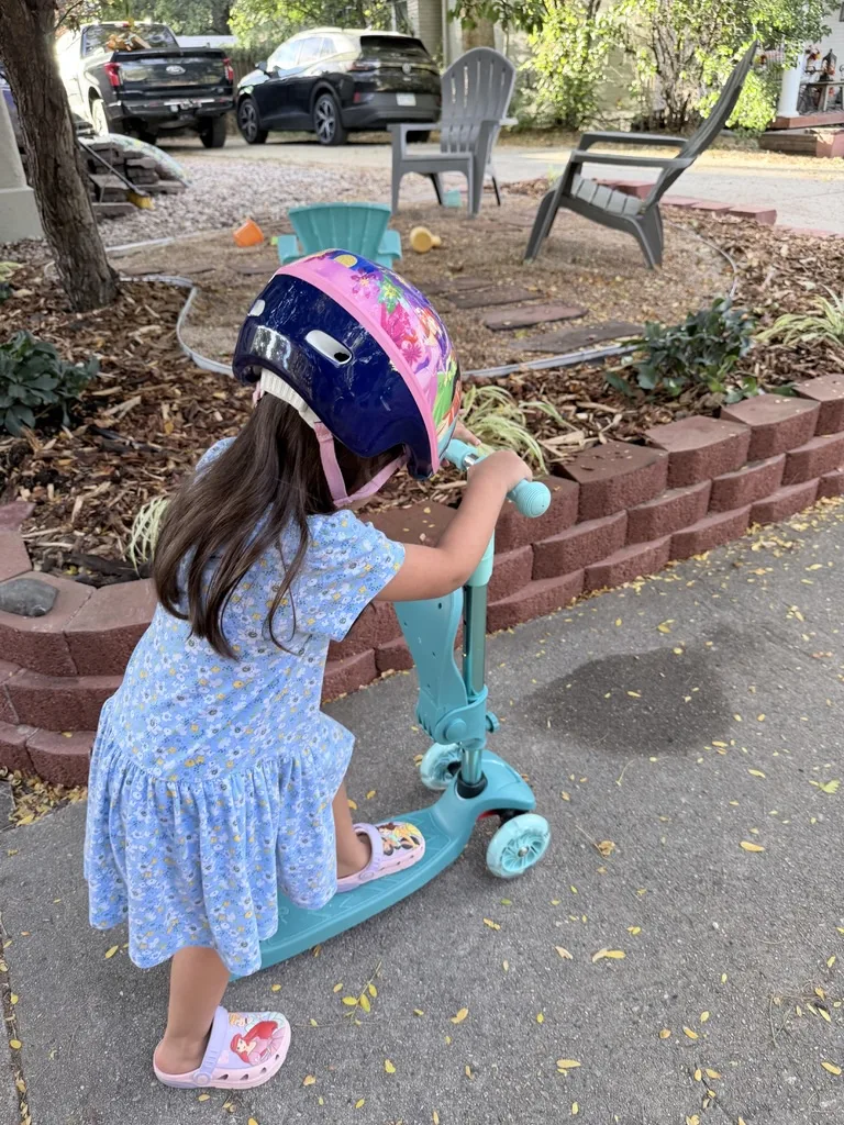 Child pushing off on a Retrospec Chipmunk Plus scooter with the folding seat flipped up against the handlebar stem
